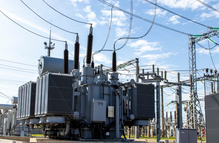 High voltage transformer against the blue sky. Electric current redistribution substation